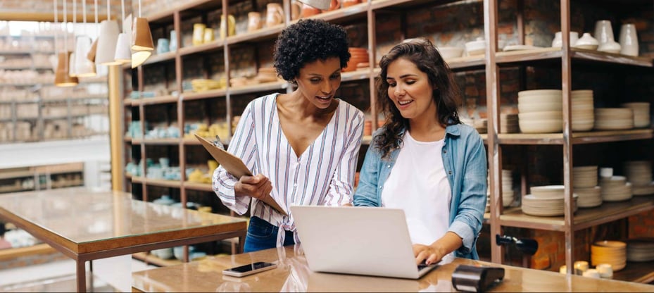 two retail employees talking in front of computer